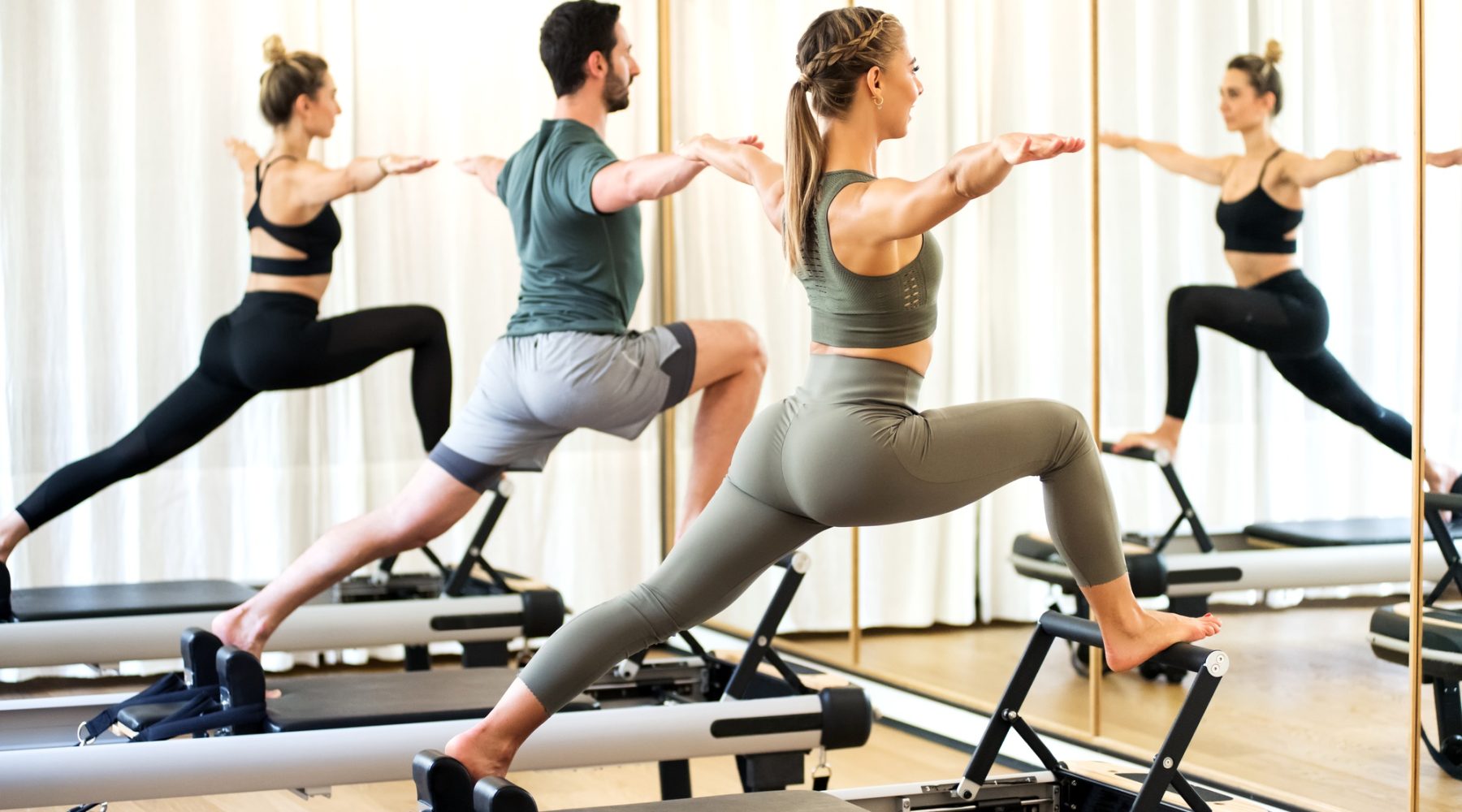 Class in a gym doing pilates standing lunges